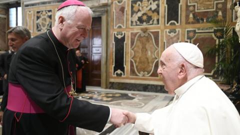 Bishop Bosco MacDonald shaking hands with Pope Francis. They are both wearing ceremonial clothes