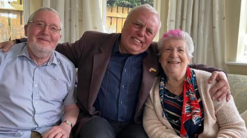 Valerii sitting on a sofa with Brenda and Brian Dinsdale