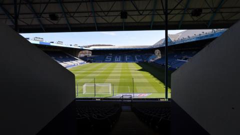 Sheffield Wednesday's Hillsborough stadium from an entrance tunnel to the stadium, with sunlight shining over the stadium