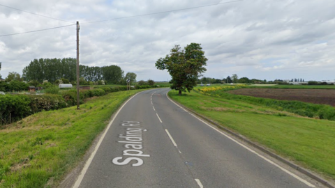 A section of Spalding Road surrounded by fields either side of the road, with a ditch both sides.