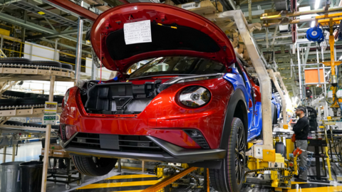 A car being built at Nissan's Sunderland factory. It is in the air on a conveyor with another car behind it.