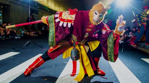 A man dressed as the Monkey King performing on a road