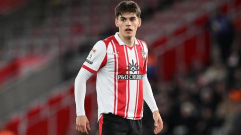 Southampton's Tom Fellows looks slightly to his right with a focused expression and his mouth slightly open. He wears a red and white vertically striped Southampton shirt.