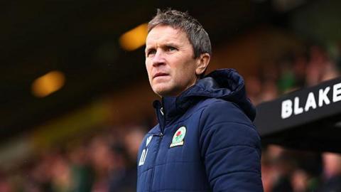 Damien Johnson on the touchline during a game between Norwich City and Blackburn Rovers. He is wearing a dark blue Rovers coat with the club badge on it