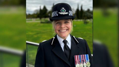 A head shot of DCC Katy Barrow-Grint in police uniform with four medals on her lapel and smiling to camera