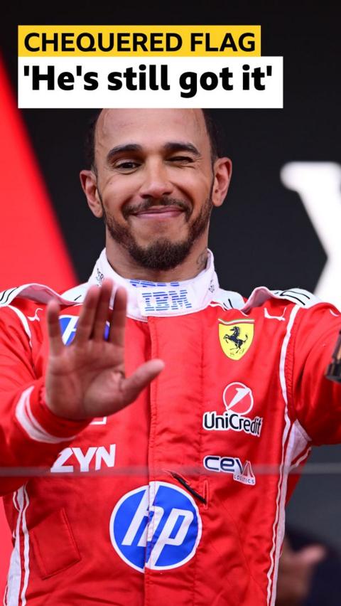Lewis Hamilton smiles and waves a hand