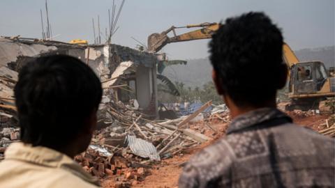 Bulldozer being used to demolish alleged illegal structures during an anti-encroachment eviction drive in India's Assam state