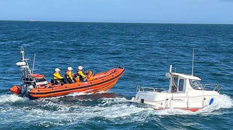 A lifeboat crew approach the sinking boat