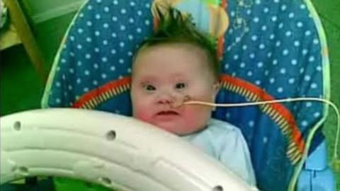 Baby with brown hair in a bouncer