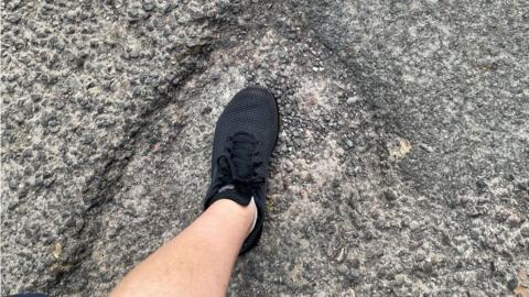 A man's foot inside a pothole