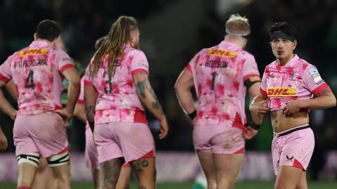 Harlequins player Marcus Smith looks dejected as his team-mates walk the other way with their backs to the camera