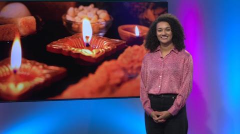 Nina in the Newsround studio with candles in the screen