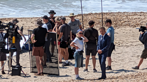 Film crews on a beach in Dorset near the sea on a sunny day