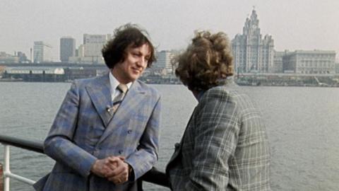 Ken Dodd on the Mersey ferry with the Liver Building in the background, talking to Nationwide reporter Michael Barratt.
