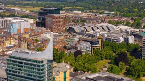 An aerial view of Reading, with a large glass building and the town's train station dominating the setting.