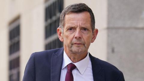 A man in a suit. Blue jacket, red tie, white shirt