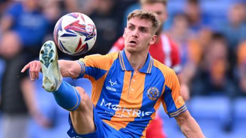 Shrewsbury Town striker George Lloyd stretches his leg up to control the ball during a game