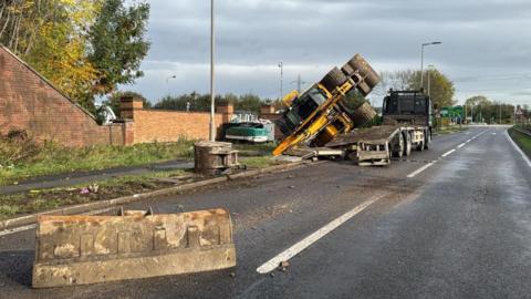 A closed road with a lorry and an overturned digger. 