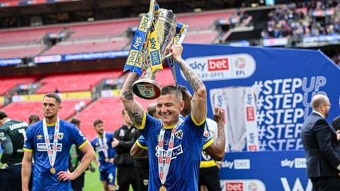 James Tilley holds the League Two play-off final winners' trophy above his head