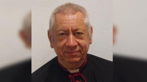 An elderly male vicar. 
