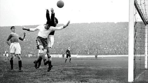 A black and white photograph showing Everton's Dixie Dean in action against Chelsea goalkeeper Millington at Stamford Bridge, London in 1932