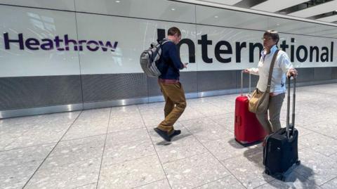 An image of two passengers walking through Heathrow airport. 