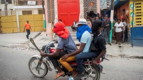 Three men on motorcycle, two of them showing machetes, are heading to block the street leading to the house of the President of Haiti, Jovenel Moise, during a new day of protests in Port-au-Prince, Haiti, 24 February 2020
