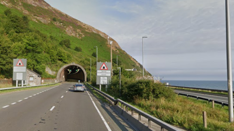 A dual carriageway by the sea with one direction going into a tunnel