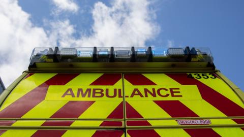 A stock image of an ambulance, with blue lights on 