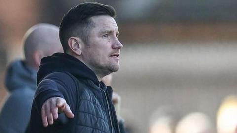 Crewe manager Lee Bell points out instructions to his players during a match