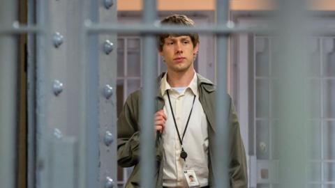 A man walking into prison. You can see him through the bars. He's carrying a rucksack 