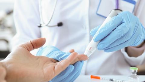 Close up of a doctor with gloves on piercing a patient's finger with a blood monitoring test machine. 