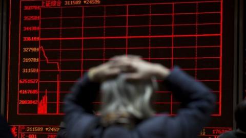 A woman reacts near a display board showing the plunge in the Shanghai Composite Index at a brokerage in Beijing, China, Thursday, Jan. 7, 2016