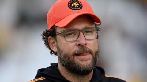 Daniel Vettori, wearing an orange Birmingham Phoenix cap, looks on