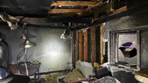 The inside of an office that has been destroyed after a fire, with debris across the floor. 