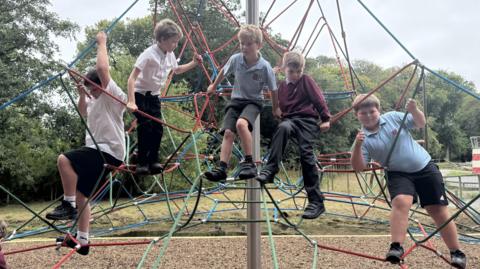 primary school boys climbing on the spiders web frame 