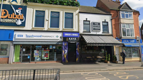 A view of the entrance to Kaya Lounge which is a door between a coffee shop and a pharmacy