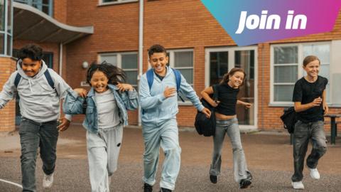 A group of five children run our fo school, smiling.