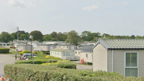 A large number of single-storey static caravans in white, some with green roof tiles and others with grey tiles.