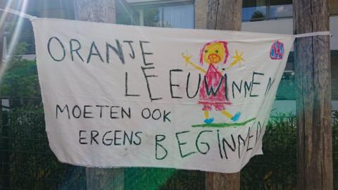 A banner reads "Orange Lionesses must also start somewhere" at the De Buut primary school playground