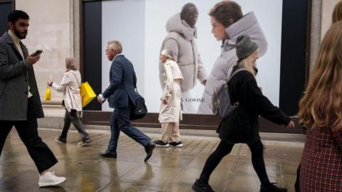 Shoppers walk down a rainy Oxford Street