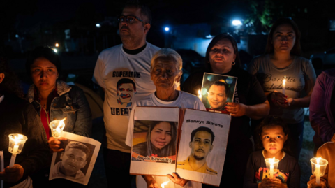 People participate in a vigil outside the Rodeo I prison in Zamora holding up images and candles