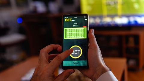 Betting on a smartphone while watching a football match on TV