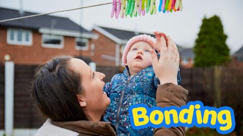 Mother and baby playing with washing line.