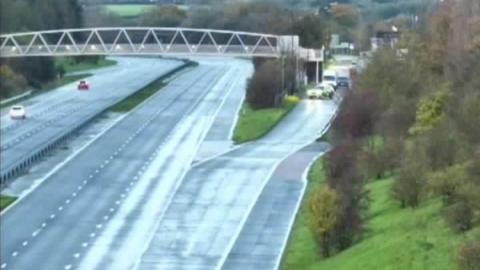 The M5 motorway near Stroud. The motorway is noticeably empty, with a police car across the slip road holding traffic. Traffic is queueing up behind the marked police car, which is spread across both lanes of the entry slip way.