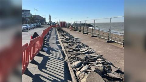 A seafront path in Herne Bay which has been cordoned off with red, plastic barriers. Half the pavement is torn up.