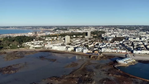 An aerial shot of Jersey seen with part of the water at the front as well as buildings in the background.