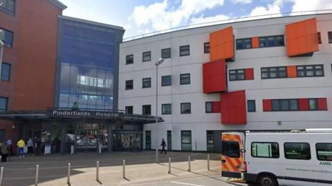 The outside of Pinderfields Hospital in Wakefield. An ambulance is parked outside.