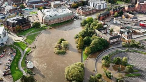 An aerial view of the River Derwent in Derby city centre. It shows the river has topped the banks and flooded flats and car parks.