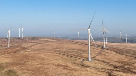 A computer generated image of the proposed Scout Moor Two windfarm.   There are several large white turbines spaced out across the moor.
